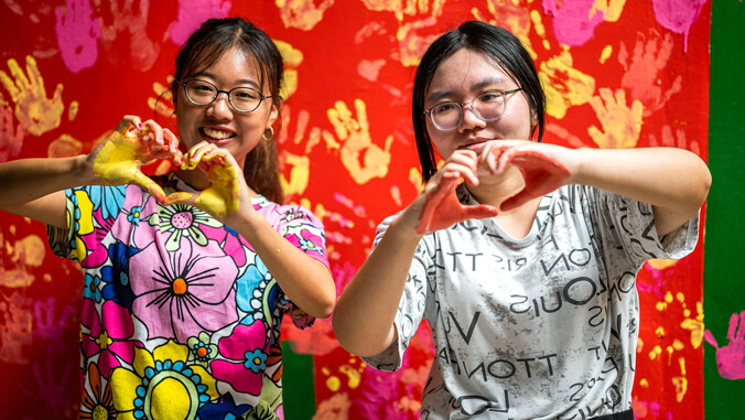 two student making hearts with their hands